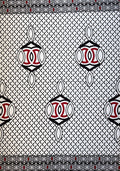 A close-up of a patterned textile or wallpaper featuring a black and white geometric lattice background with repeating red and black diamond motifs and decorative borders.
