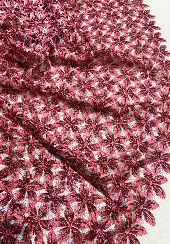 red and pink floral lace fabric with a repeating embroidered starburst pattern